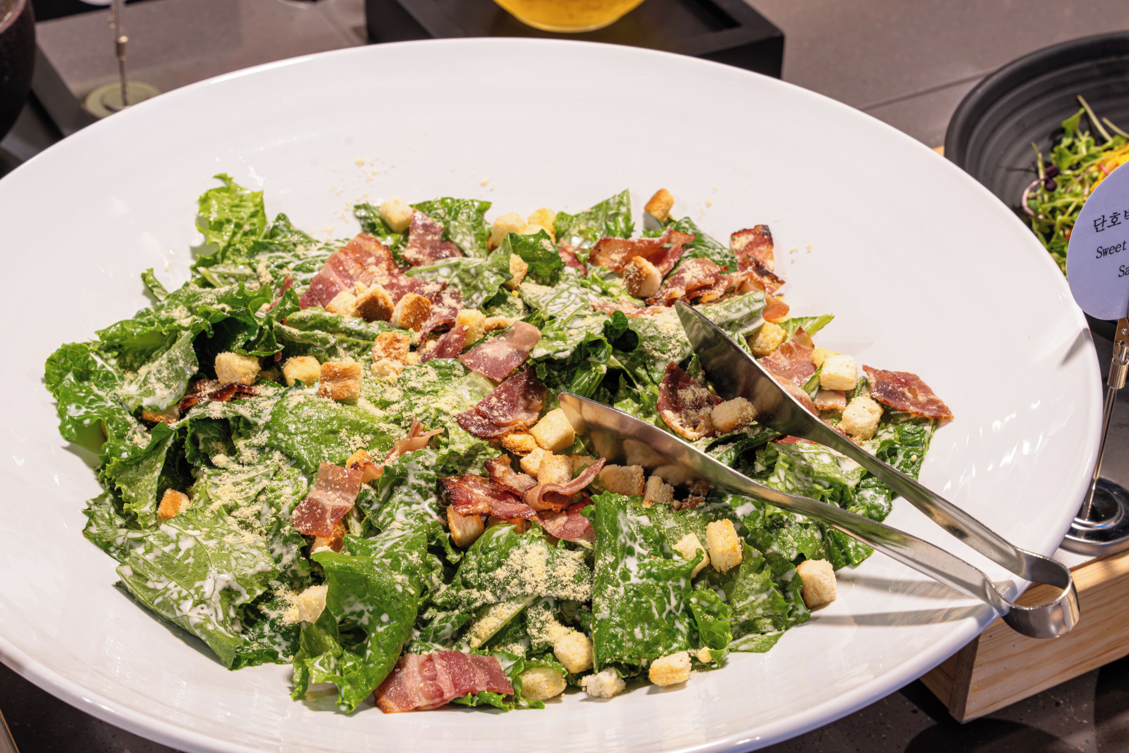 Ein Teller Caesar Salat mit Croutons und Speck.