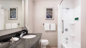 Une salle de bain moderne avec un comptoir en granit, un lavabo blanc, des toilettes et une douche à l’italienne.
