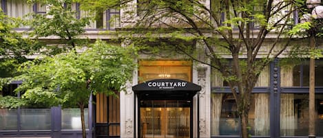 A hotel entrance with a marquee sign, a glass door, and a tree in front.