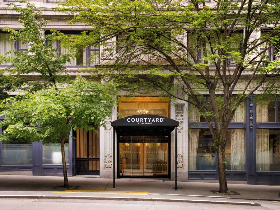 A hotel entrance with a marquee sign, a glass door, and a tree in front.