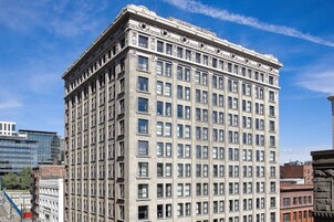 A tall, multi-story building with a classical architectural style, featuring numerous windows and decorative elements on the facade.