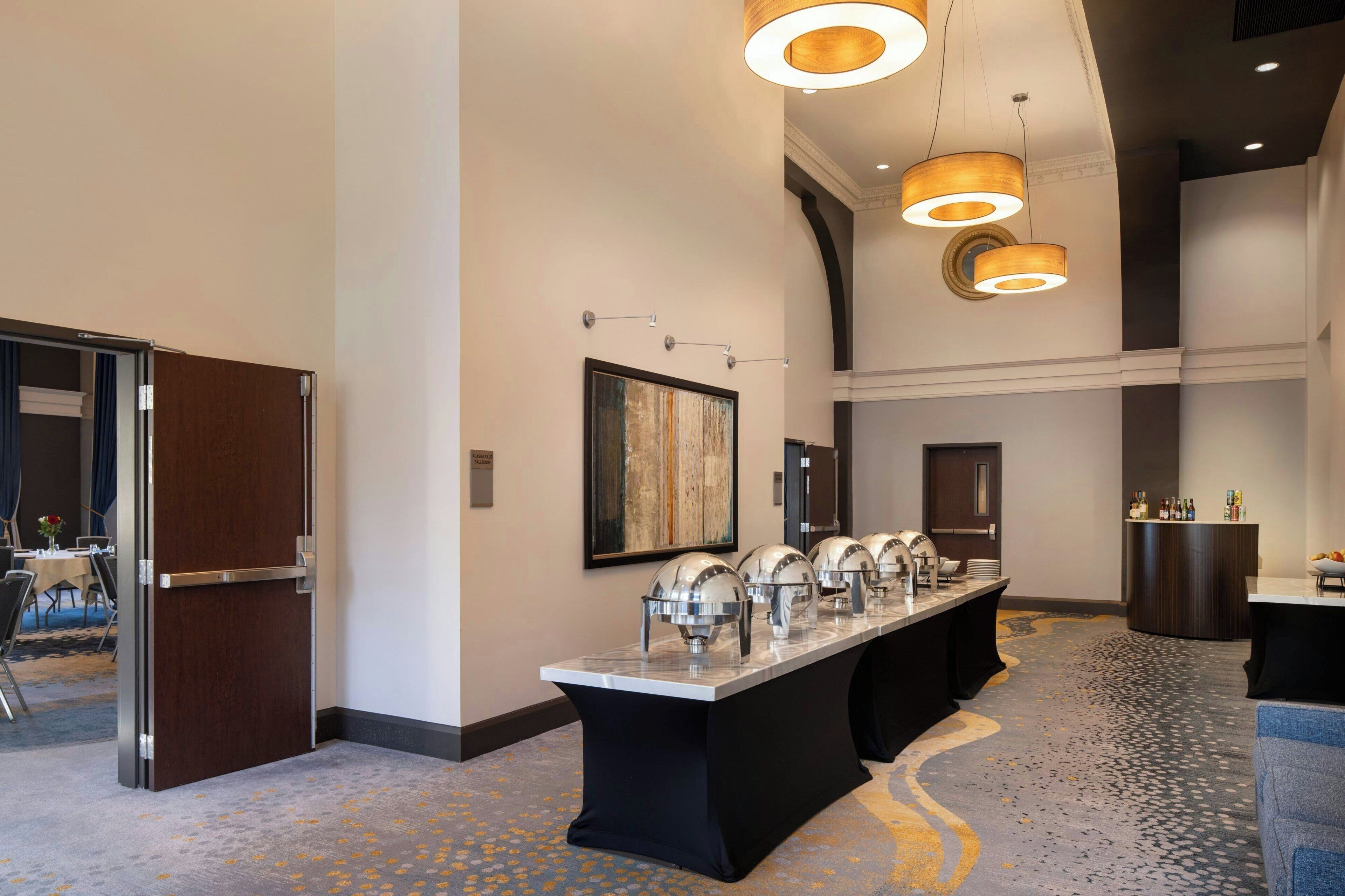 Eine Hotelhalle mit einem Buffet, einem großen Gemälde an der Wand und einem Empfangstisch.