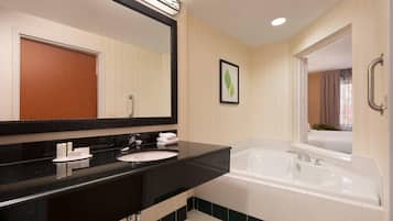 A modern bathroom with a black countertop, white sink, and a large bathtub.