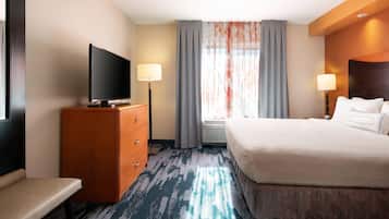 Habitación de hotel con una cama grande, televisión de pantalla plana, escritorio y ventana con cortinas.