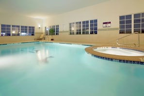 An indoor swimming pool with clear water, a diving board, and a sign indicating no diving.