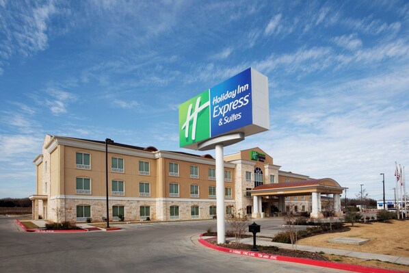 A Holiday Inn Express & Suites hotel with a large sign, a covered entrance, and a fire lane.