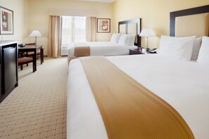 A hotel room with two beds, a desk, and a chair.