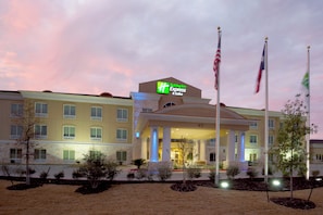 A Holiday Inn Express hotel with a prominent entrance, multiple flags, and a well-lit facade.