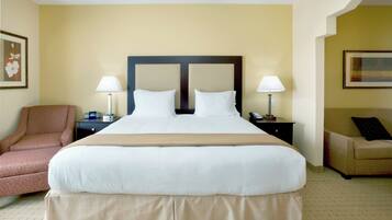 A hotel room with a large bed, two bedside tables, a chair, and a sofa.