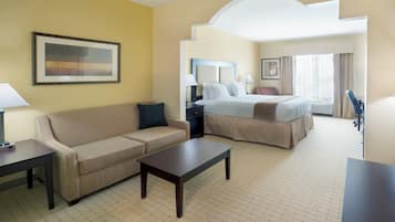 A hotel room with a bed, a sofa, a coffee table, and a desk.