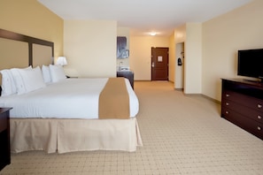 A hotel room with a large bed, a dresser, a television, and a bathroom visible in the background.
