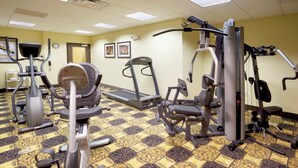 Un gimnasio con cintas de correr, elípticas y equipo de pesas.
