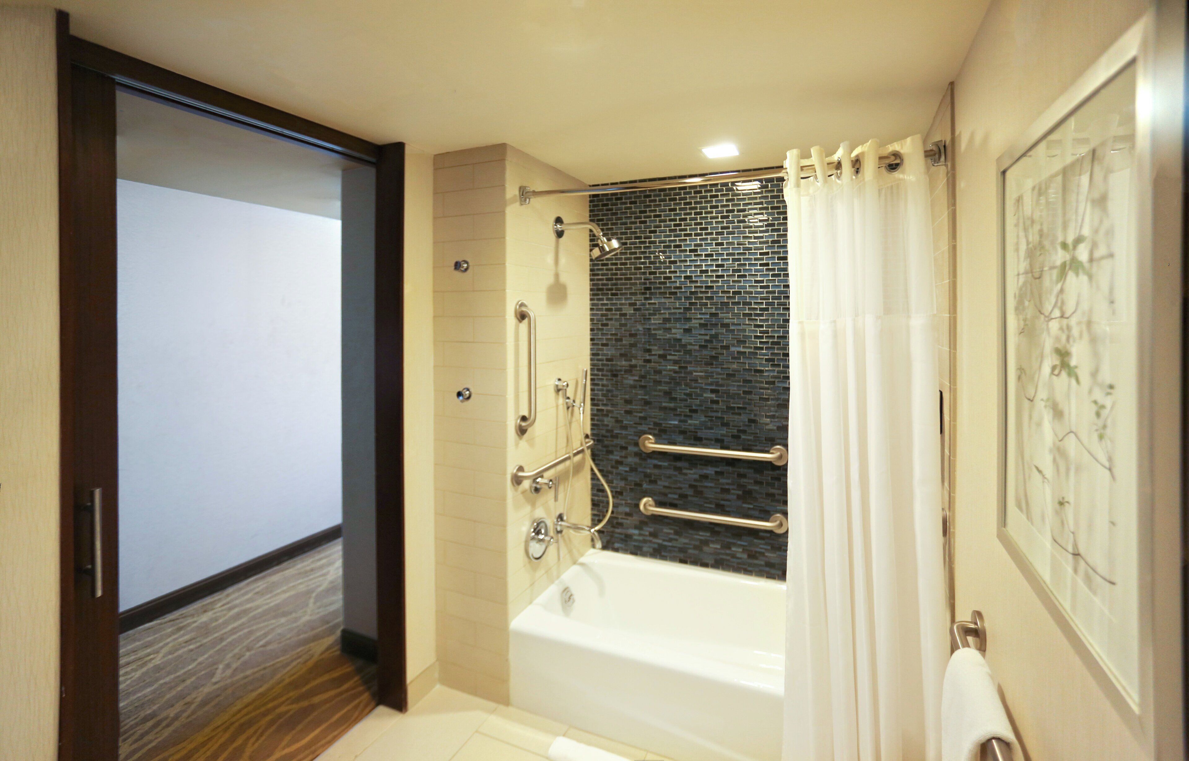 Ein modernes Badezimmer mit Badewanne, Dusche und Duschabtrennung aus Glas.
