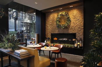 A bar area with a long counter, multiple hanging light fixtures, and a variety of bottles and glasses. at InterContinental New York Times Square by IHG