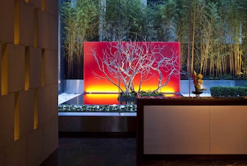 Two people sitting at a table with a city view, a glass of drink, and a vase with flowers. at InterContinental New York Times Square by IHG