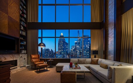 A modern living room with a large window, a leather sofa, a coffee table, and a fireplace.