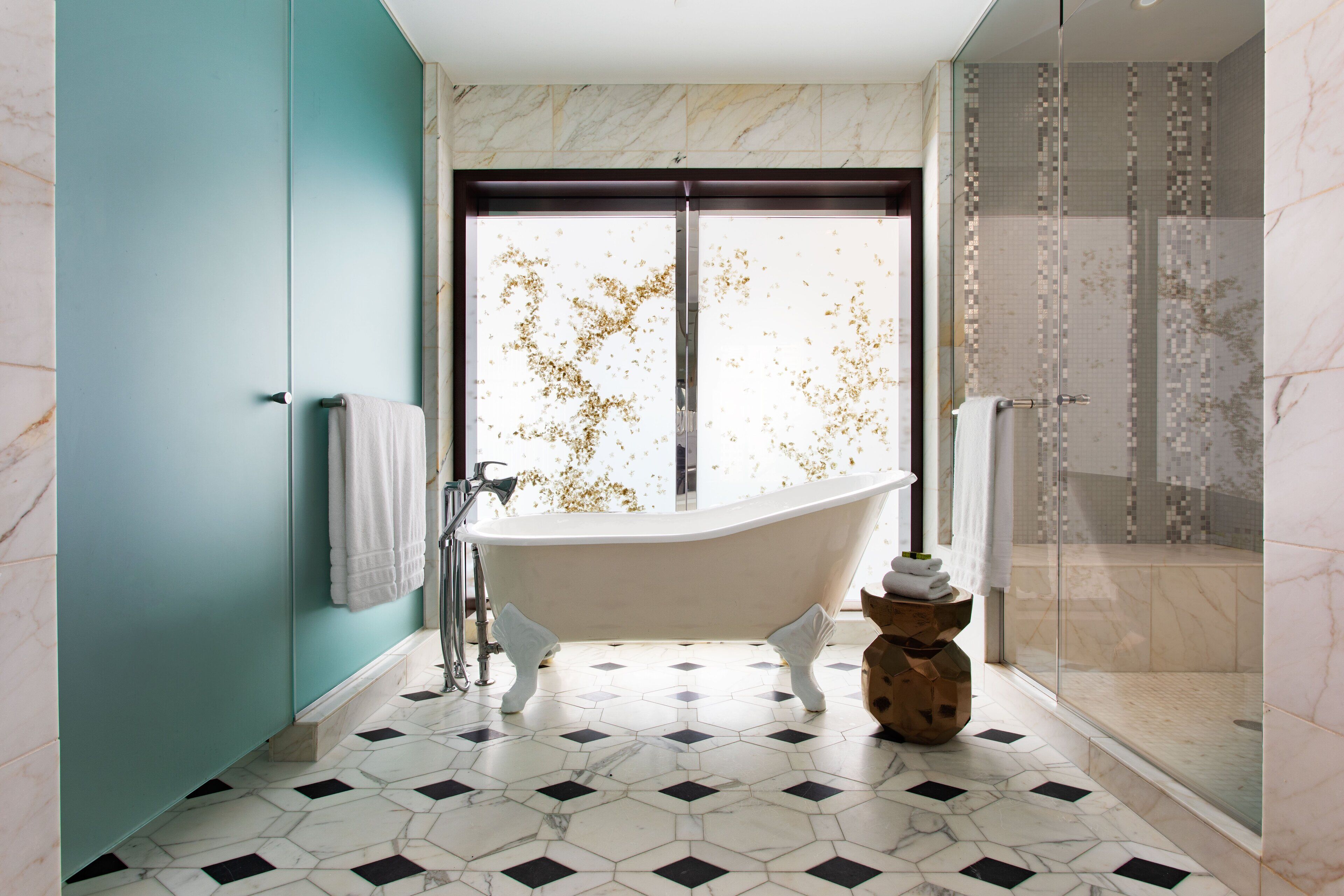 Un baño con una bañera independiente, cabina de ducha de vidrio y suelo de baldosas.