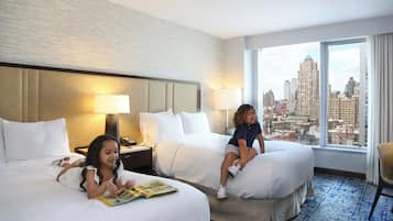 Habitación de hotel con dos camas, vista a la ciudad y un ventanal grande.