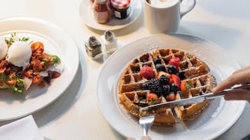 A breakfast setting with waffles topped with berries and a scoop of ice cream on a plate.
