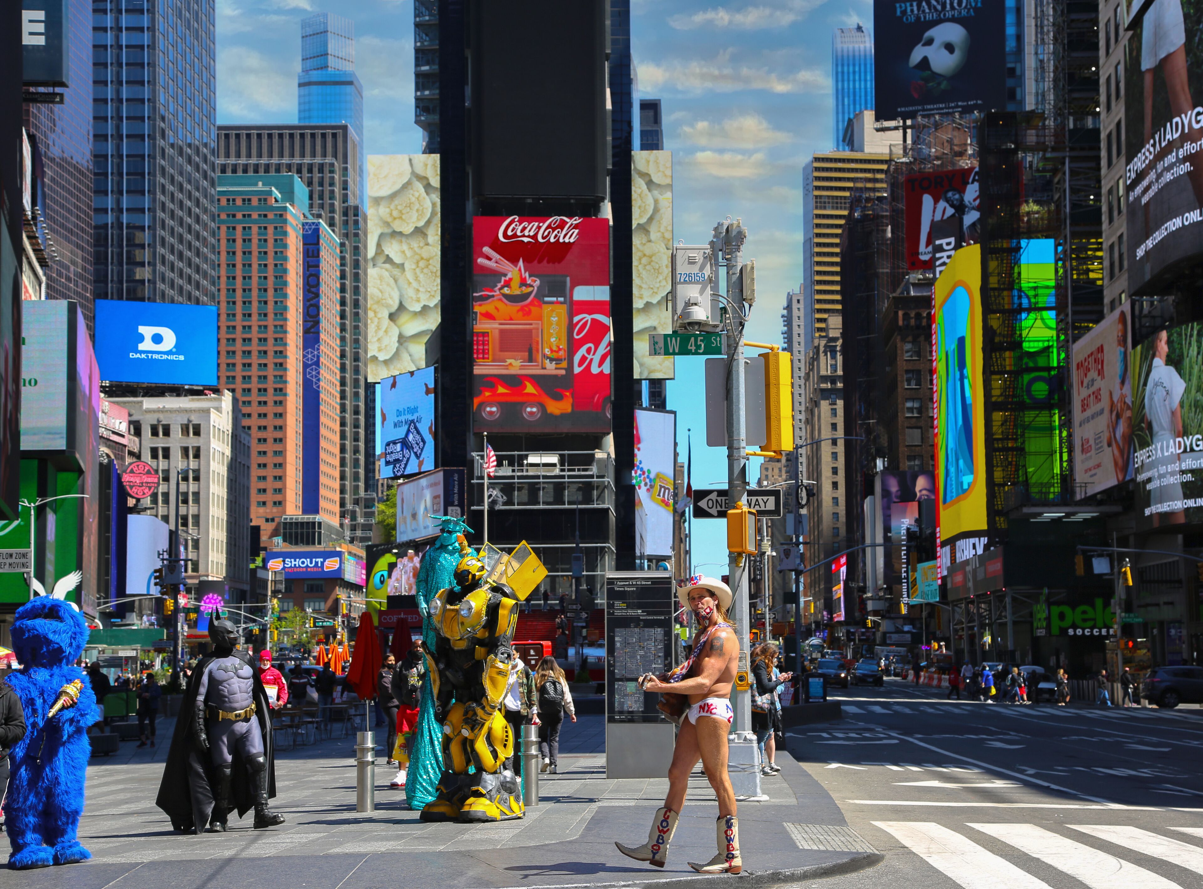 A busy urban street with tall buildings, billboards, and a crosswalk.