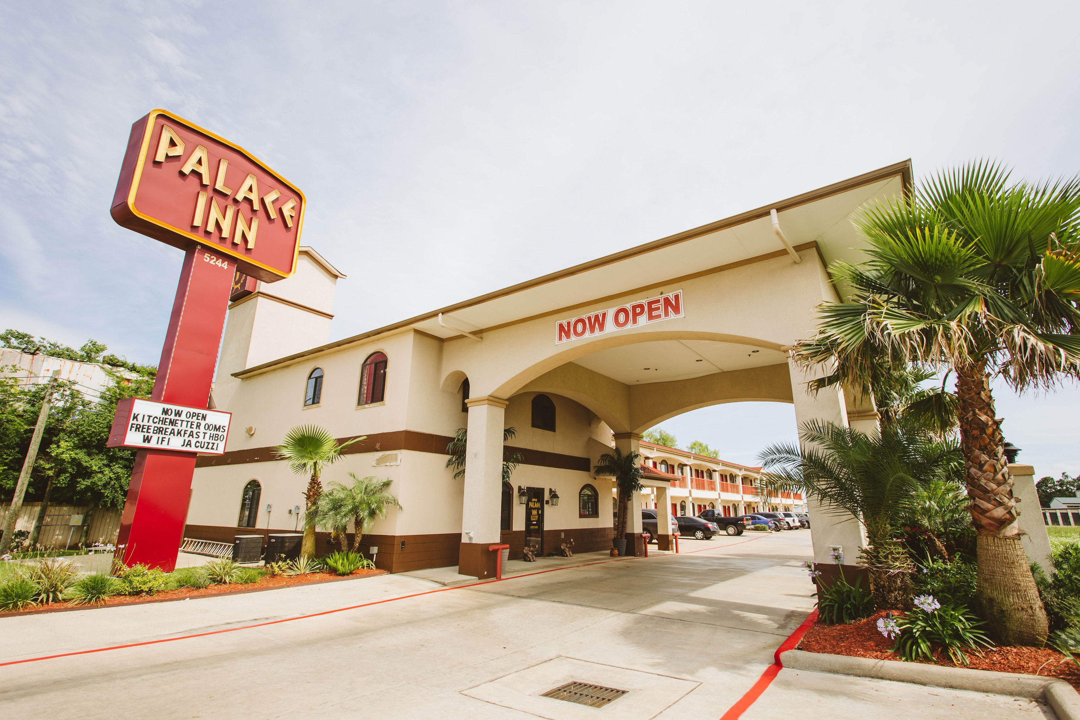 A hotel entrance with a sign reading "PALACE INN NOW OPEN."