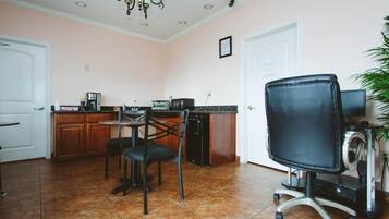 A kitchen with a dining area, a black office chair, and a small table.