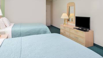A hotel room with two beds, a TV, a dresser, and a mirror.