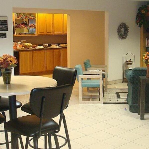 A dining area with a round table, four chairs, a small side table, and a decorative vase.