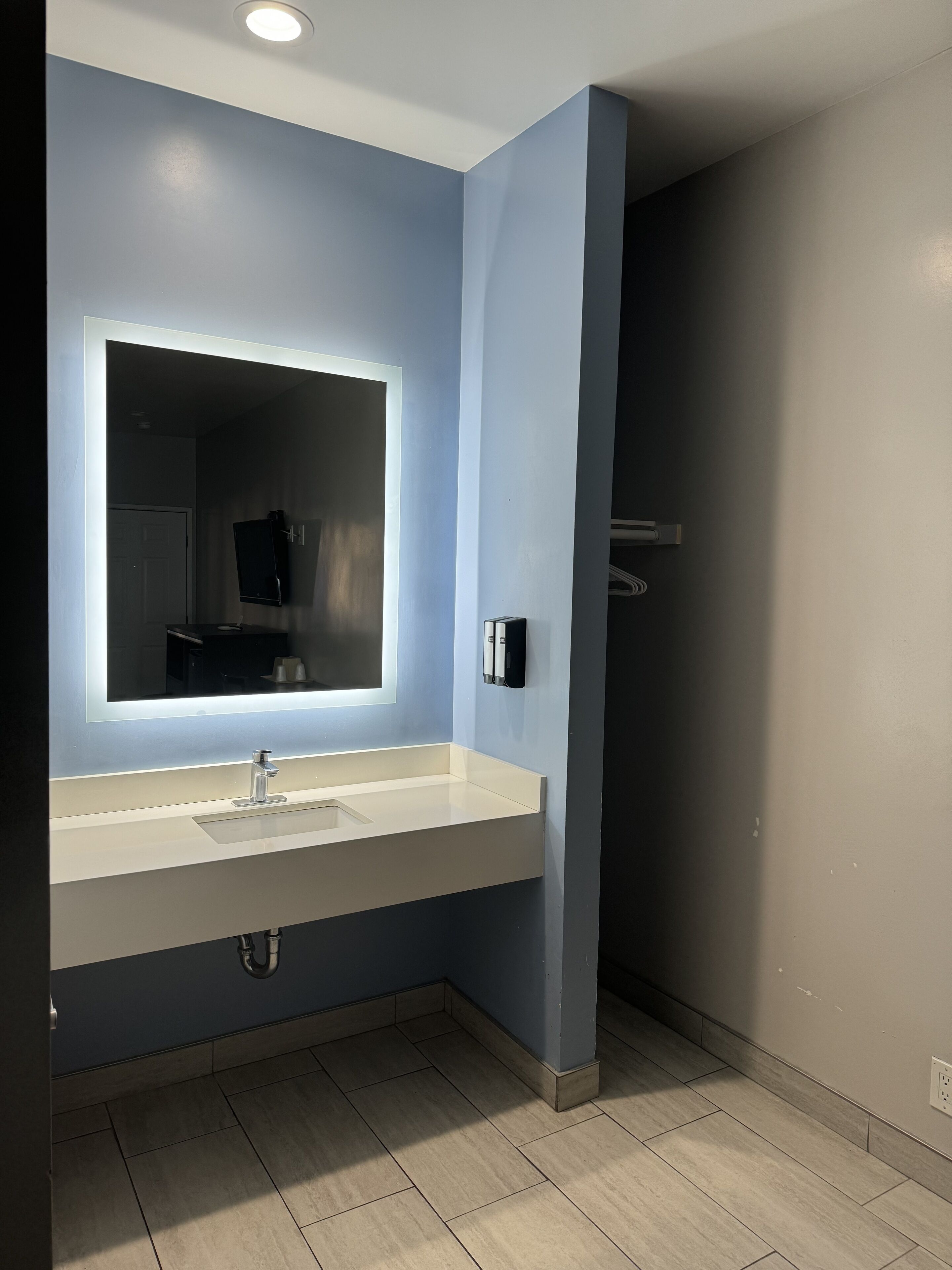 A modern bathroom with a large mirror, a sink, and a toilet.