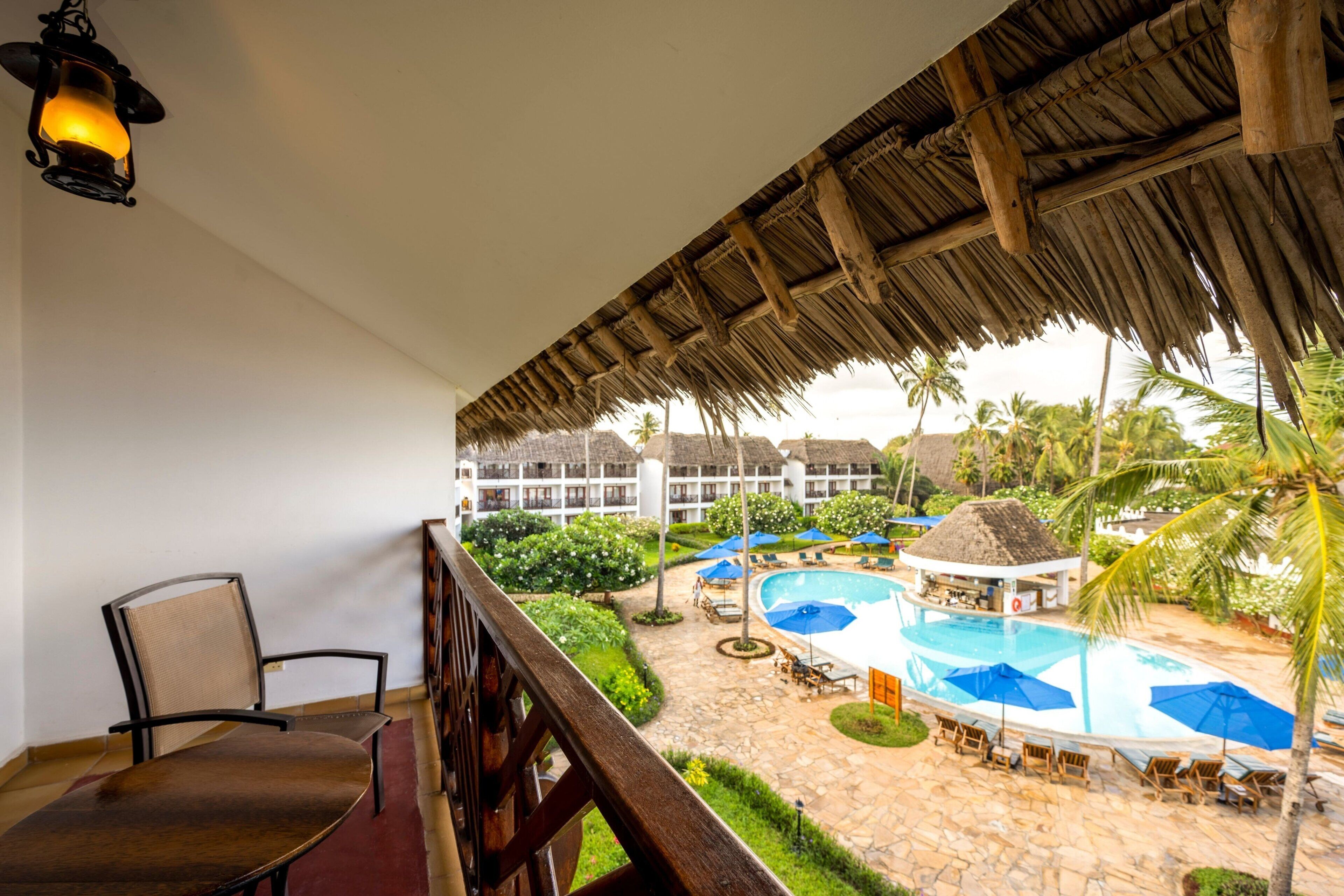 Un balcon donnant sur un espace piscine, comprenant des chaises longues et des parasols.
