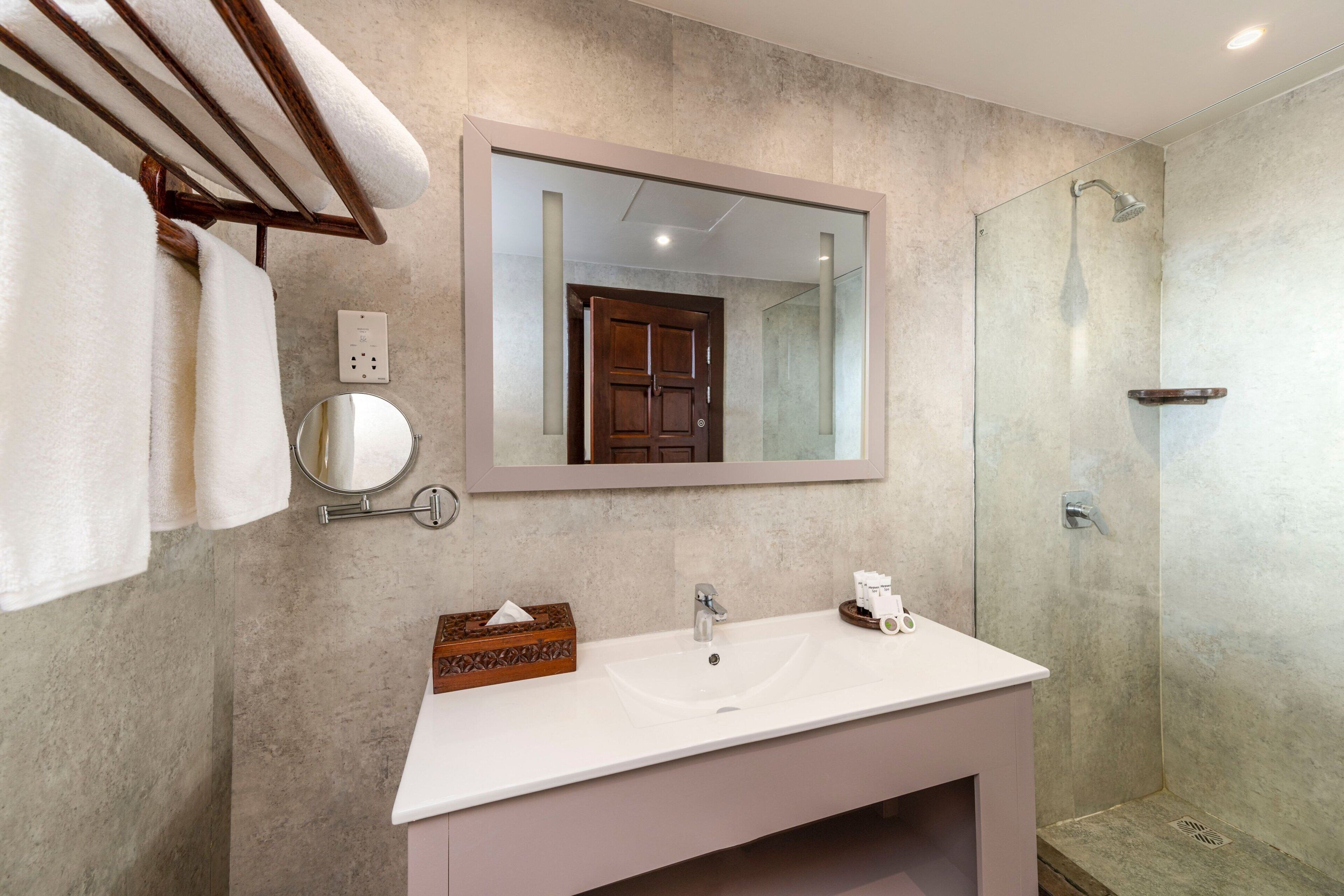 A bathroom with a white sink, a mirror, a towel rack, and a shower.