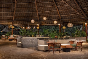 An indoor seating area with wooden furniture and a thatched roof ceiling. - Turaco Nungwi Resort, a Tribute Portfolio Hotel (Nungwi)