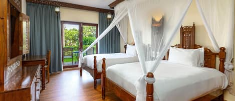 A bedroom with two wooden beds, a wooden dresser, a ceiling fan, and a view of the outdoors through a glass door.