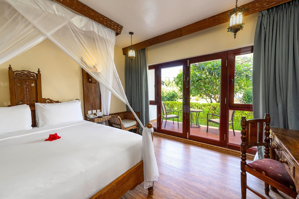A spacious bedroom with a large bed, wooden headboard, and a canopy.