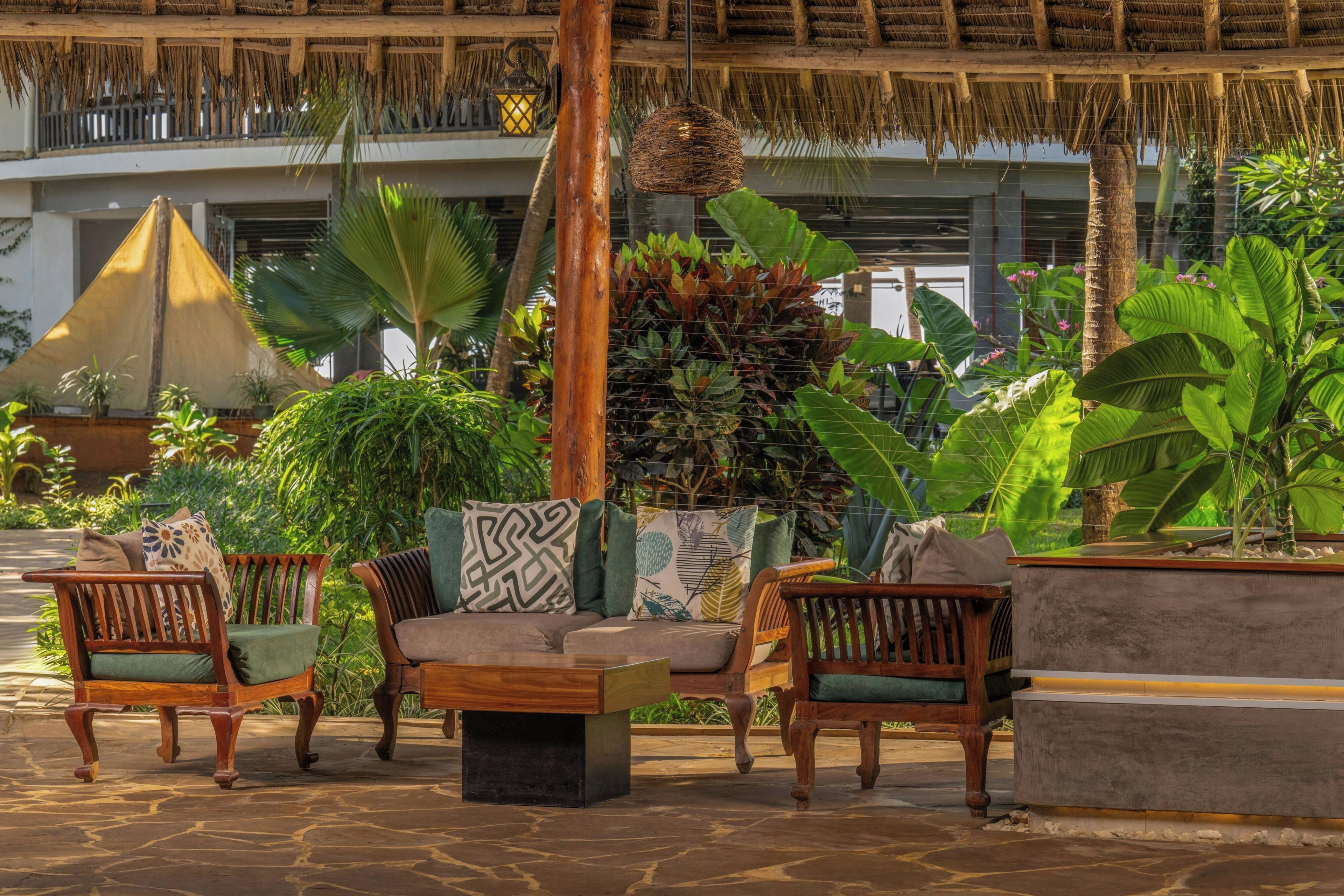 A tropical outdoor seating area with wicker furniture and potted plants.