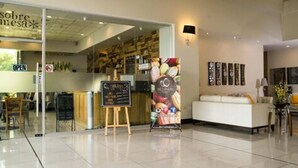 A modern interior with a reception area, a seating area, and a visible menu board.