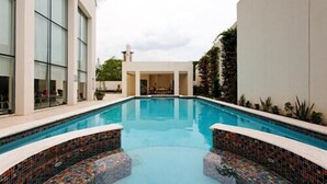 A swimming pool with a tiled edge, surrounded by a building with large windows and a white exterior.