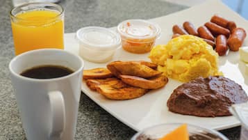 Un plato de desayuno con huevos, salchichas, tostadas y una taza de café.