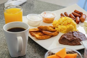 Prato de café da manhã com ovos, salsichas, torradas e uma xícara de café.