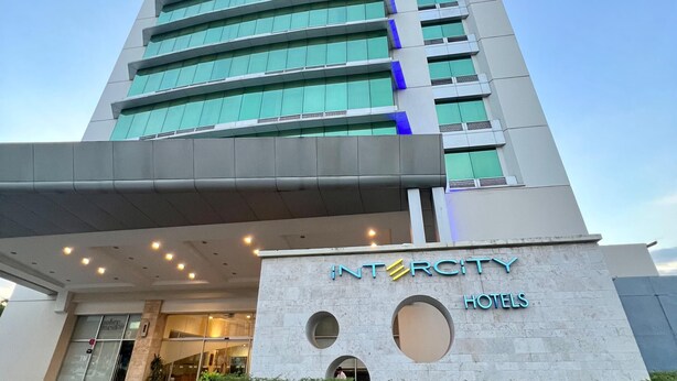 A modern hotel with a prominent entrance, a name sign, and a series of windows.