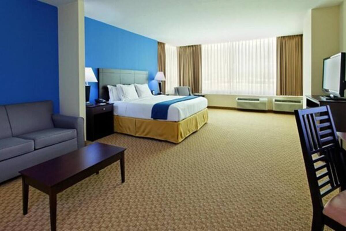 Une chambre d’hôtel avec un lit, un canapé, une télévision et un bureau.