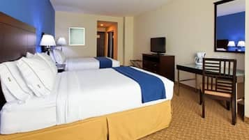 Quarto de hotel com duas camas, uma mesa, uma televisão e uma cadeira.