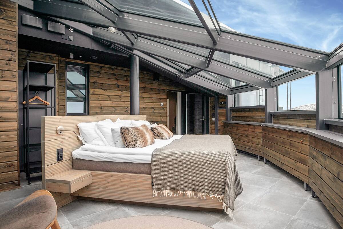 Un dormitorio moderno con tragaluz, paredes de madera y una cama con vistas.