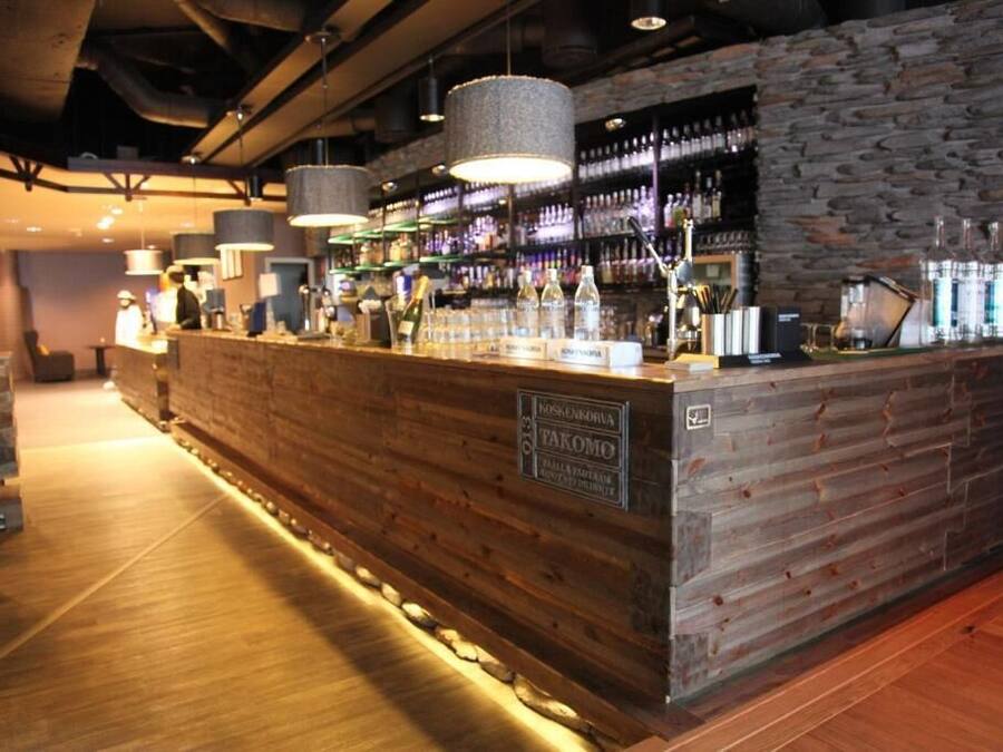 Een bar met een houten toonbank, stenen muur en hangende hanglampen.