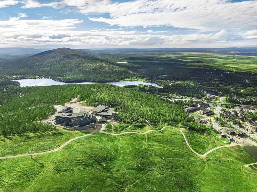 Ett flygbildsbild av ett semesterområde med en stor byggnad, flera vägar och omgivande skogsområden.