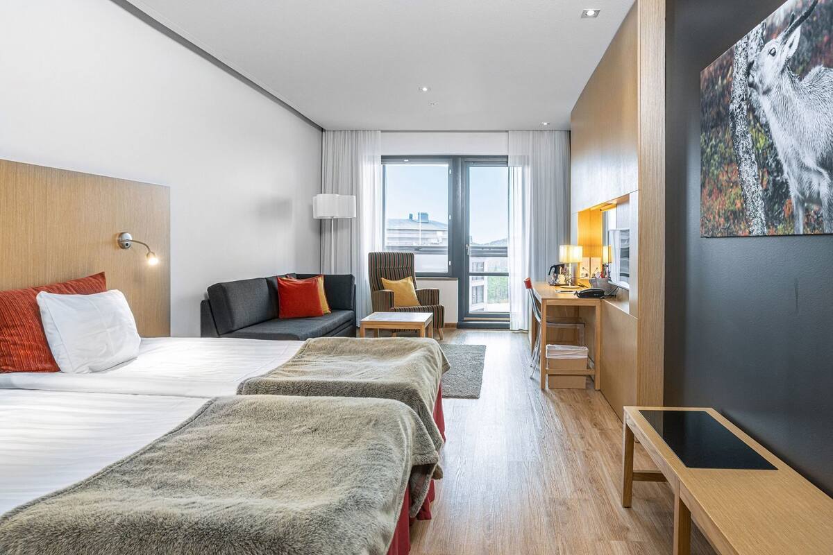 Una habitación de hotel con una cama, un sofá, un escritorio y una silla.