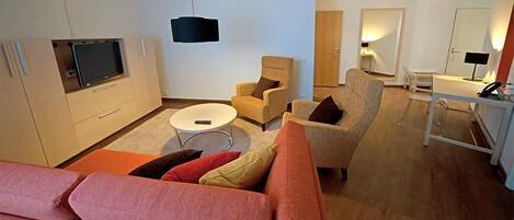 Una sala de estar moderna con un sofá, sillones, una mesa de centro y un televisor.