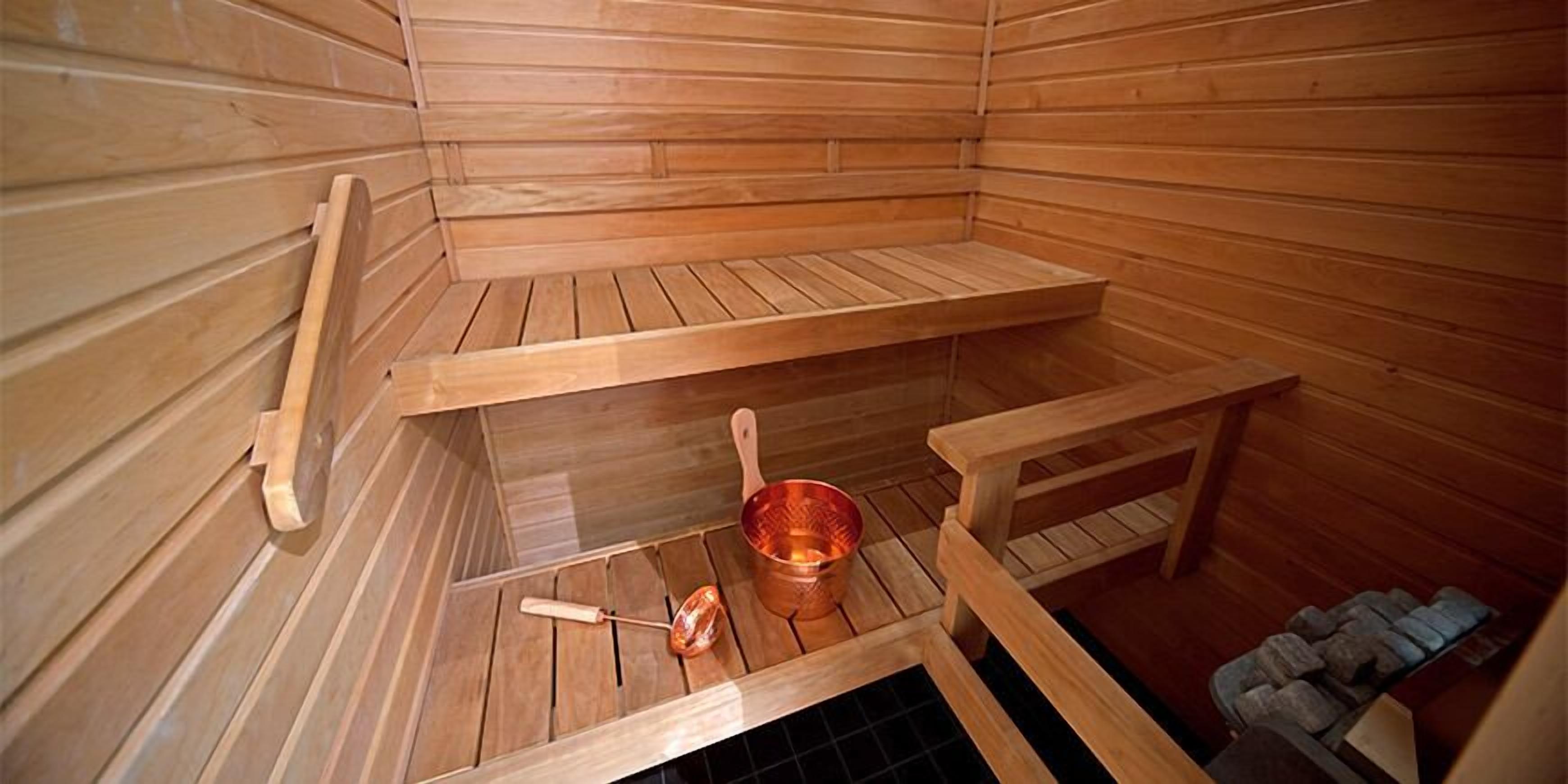 A sauna with wooden benches and a copper basin.