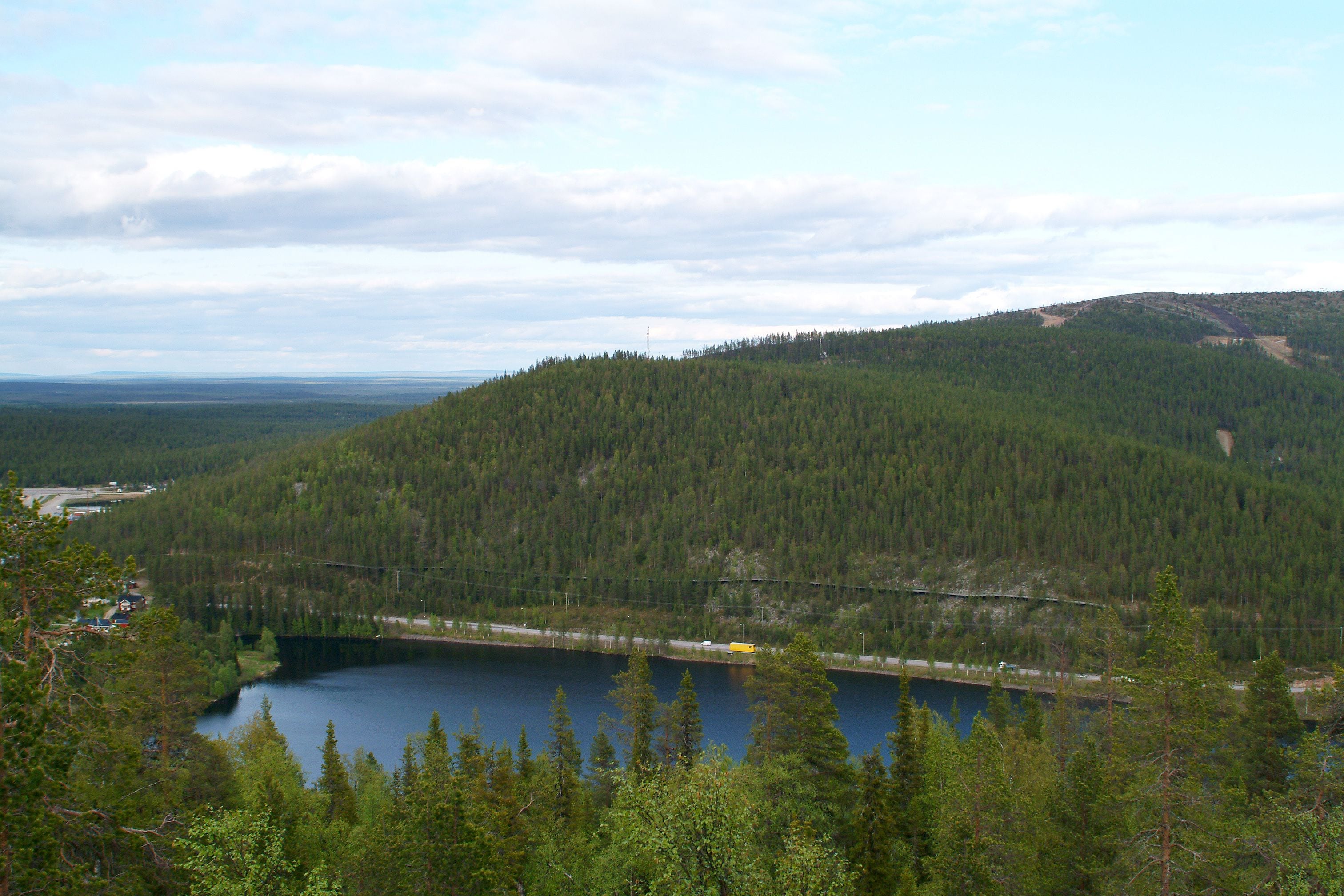 A lake surrounded by dense forest and a hilly landscape.