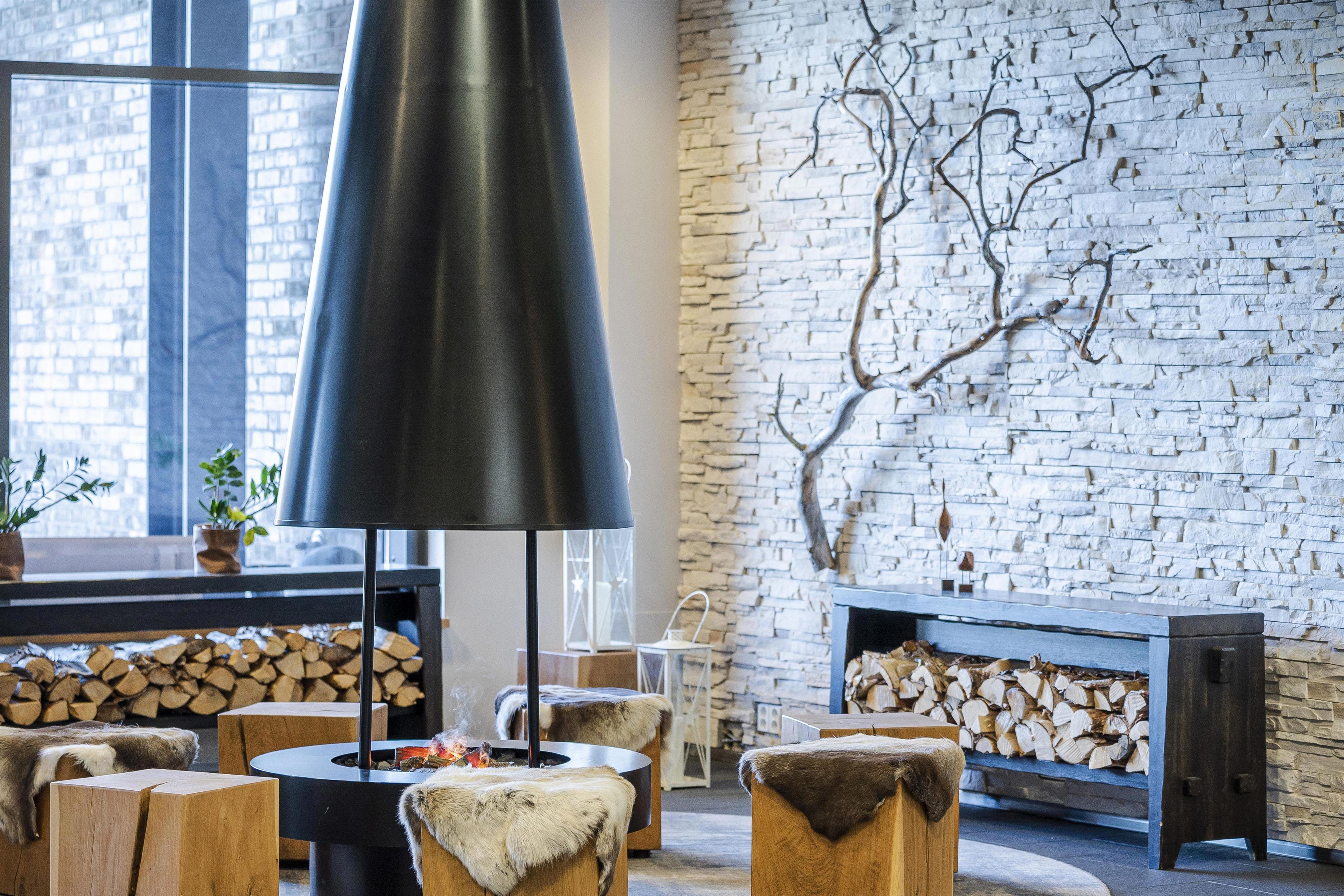 A modern interior with a fireplace, wooden furniture, and a stone wall.